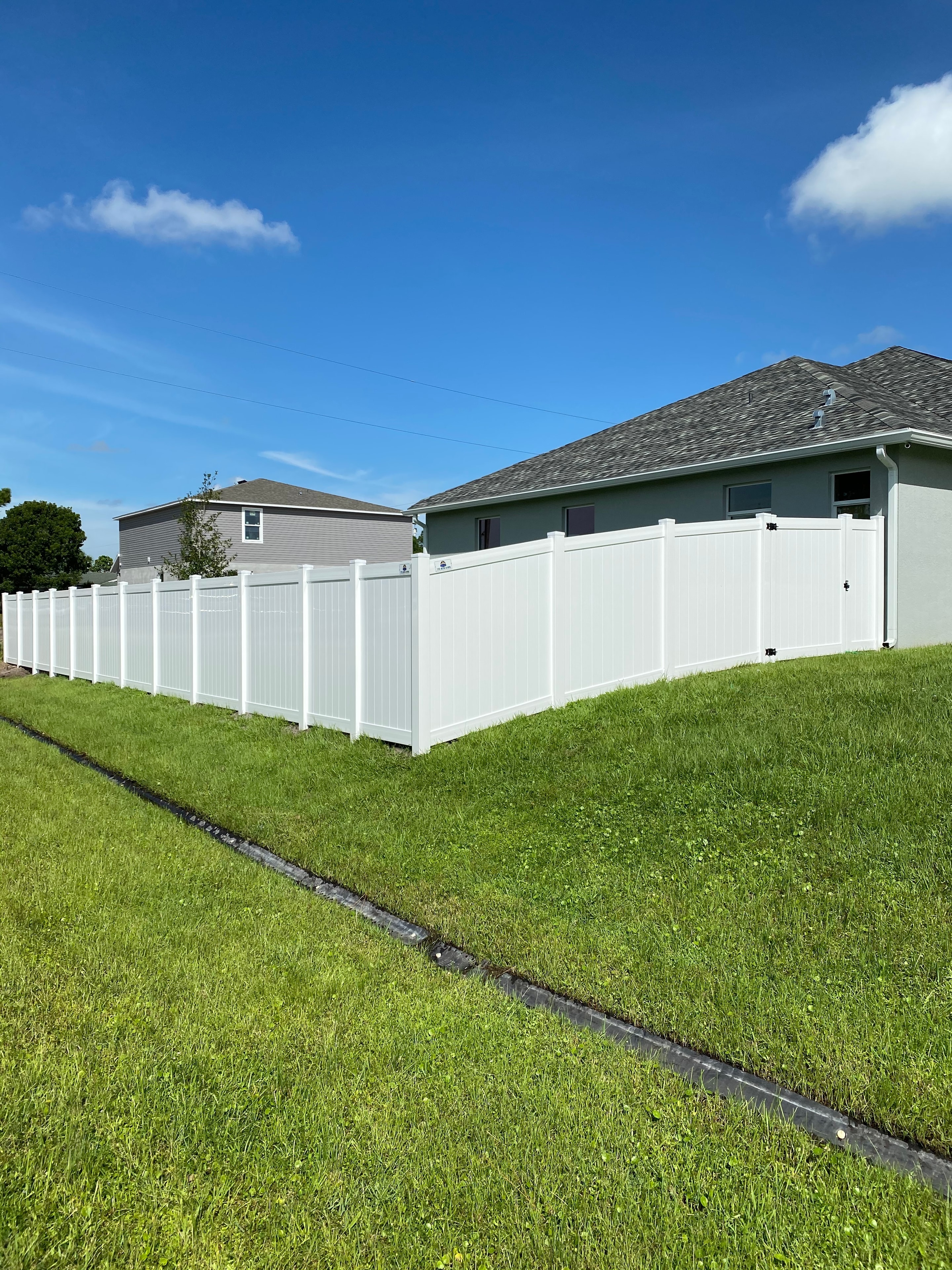 White vinyl privacy fence installed in a residential backyard